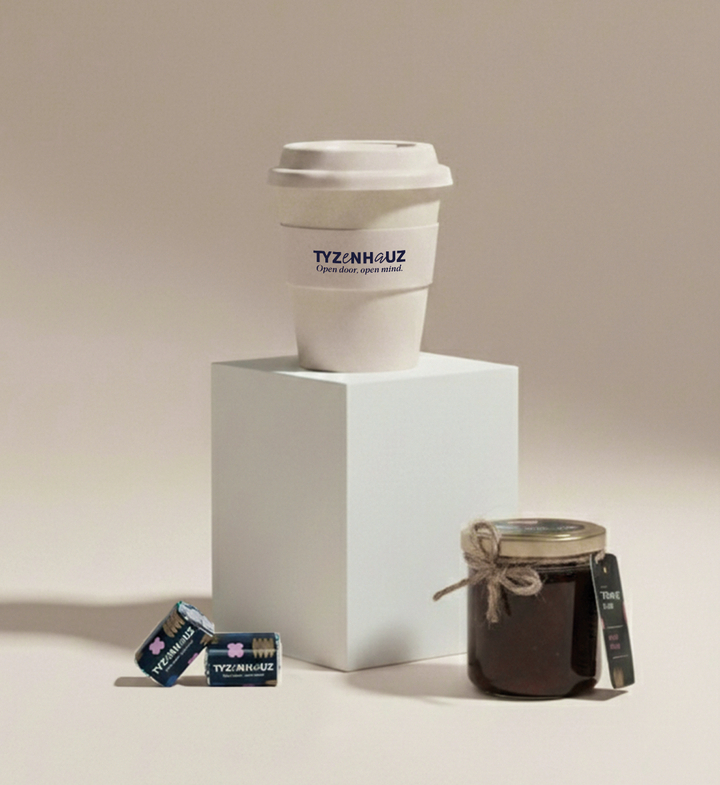 Kubek na wynos TYZENHAUZ na podstawce, obok domowy słoik dżemu i dwie zapakowane kostki cukru