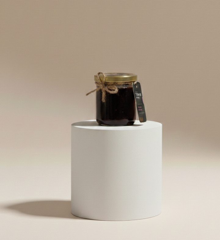 Mały słoik rzemieślniczego dżemu ze sznurkiem i etykietą na białym podium — idealny upominek powitalny lub dodatek do śniadania