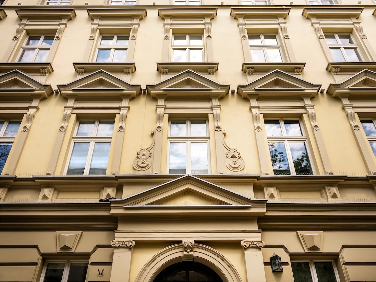 Elewacja zabytkowego budynku hotelowego z jasnożółtą fasadą i bogato zdobionymi oknami z gzymsami