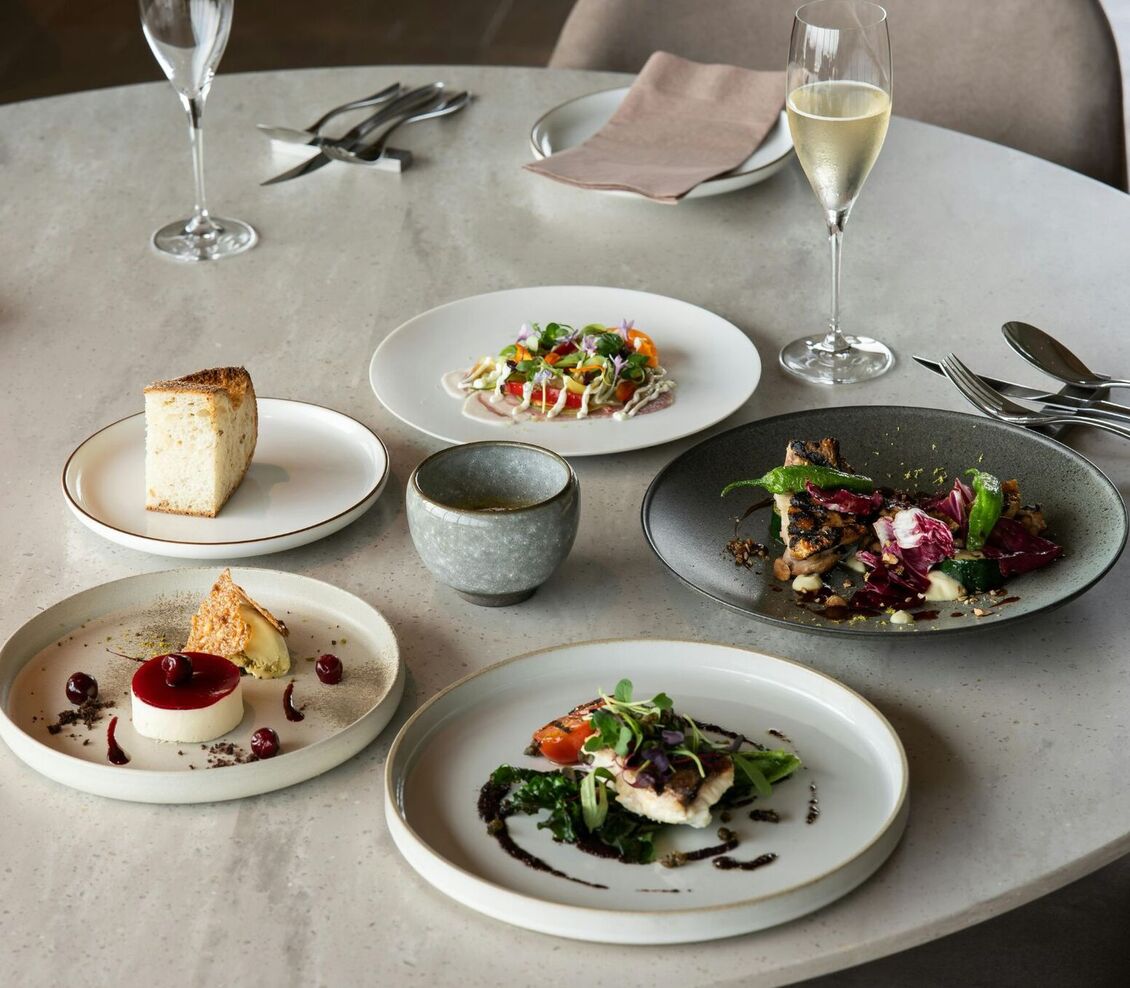 Wyrafinowane menu degustacyjne na marmurowym stole: przystawki, deser, pieczywo i kieliszek szampana