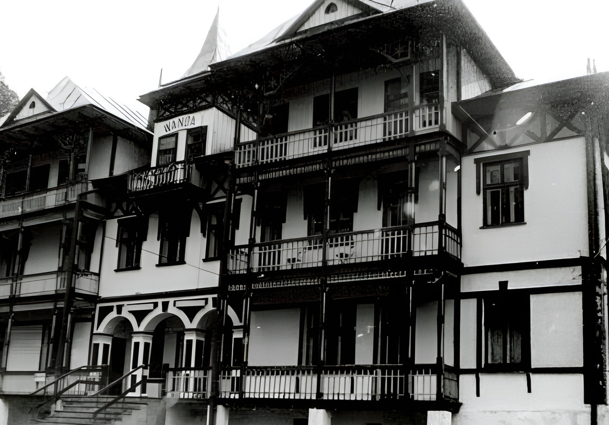 Zabytkowy pensjonat górski z rzeźbionymi drewnianymi balkonami, arkadowym wejściem i stromymi dachami, nostalgiczny klimat