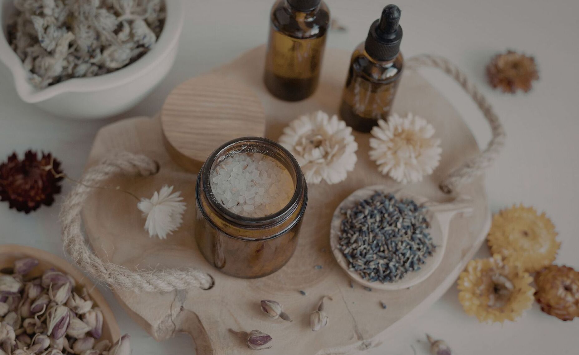 Bursztynowe buteleczki z solą do kąpieli i kroplomierzami z olejkami, suszona lawenda i kwiaty na drewnianej tacy — aromaterapia spa