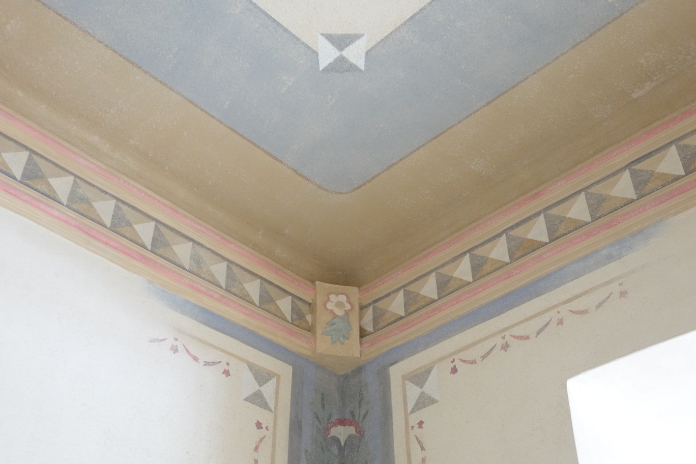Ozdobny narożnik sufitu z geometrycznym pasem, pastelową listwą i kwiatowym medalionem w stylowym pokoju