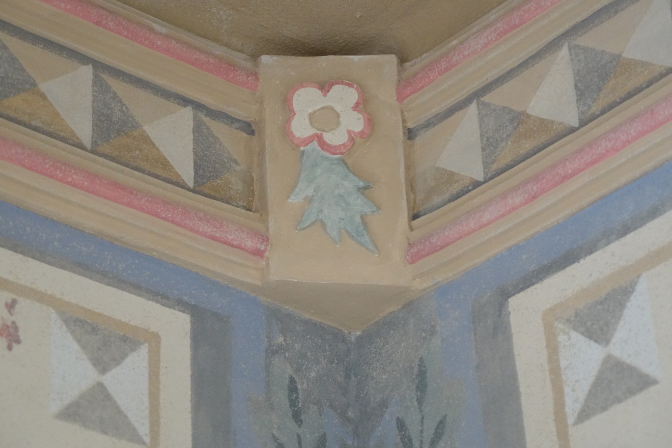 Malowany gzyms z pastelowymi geometrycznymi wzorami i kwiatowym motywem w historycznym wnętrzu hotelu