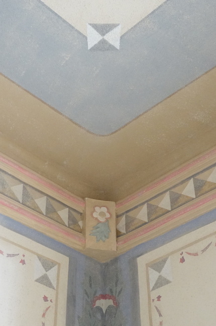 Ozdobny narożnik sufitu z geometrycznym pasem, pastelową listwą i kwiatowym medalionem w stylowym pokoju
