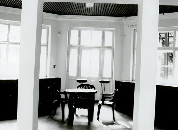 Słoneczny zakątek śniadaniowy hotelu z okrągłym stołem, krzesłami i stołkami barowymi przy wysokich oknach, drewniany sufit