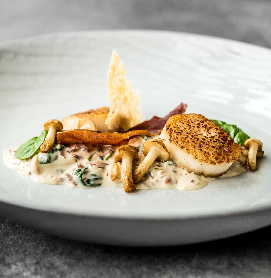 Smażone przegrzebki na kremowym sosie z grzybów i szpinaku, podane z podsmażanymi pieczarkami, chrupiącym boczkiem i płatkiem parmezanu