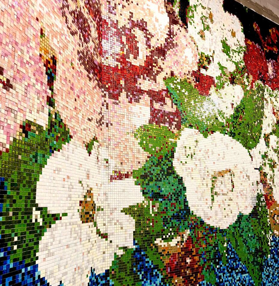 Błyszcząca mozaika ścienna z dużymi białymi kwiatami, zielonymi liśćmi i niebieskimi akcentami w hotelowym lobby.