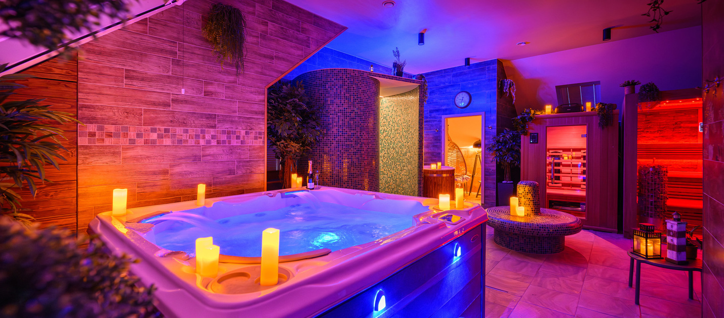 Private Spa‑Suite mit beleuchtetem Whirlpool, Kerzen, mosaikgefliester Dampfkabine, Sauna und warmen Holzakzenten