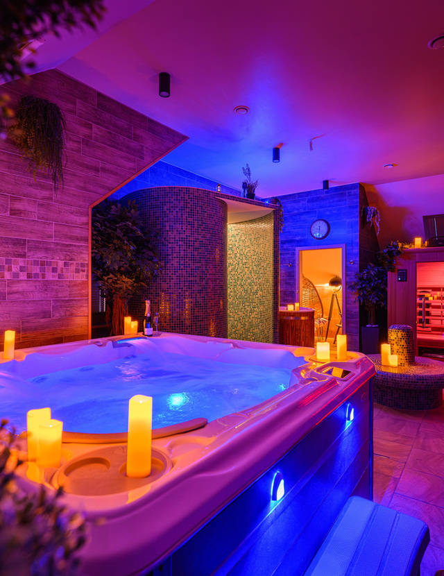 Spa wewnętrzne z podświetlanym jacuzzi, świecami, mozaikową łaźnią parową, sauną, leżakami i szampanem w nastrojowym świetle