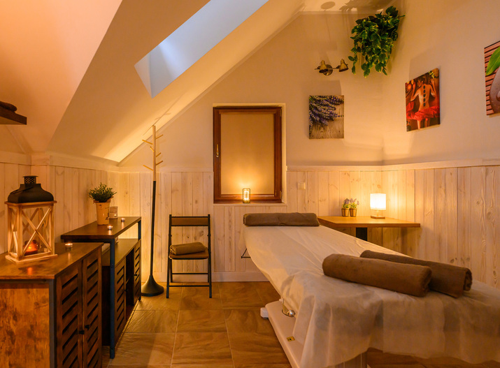 Gemütlicher Spa-Behandlungsraum im Dachgeschoss mit Massageliege, Kerzenlicht, Holzverkleidung und Pflanzen