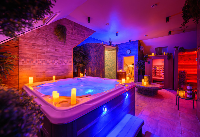 Privatus SPA su apšviestu džakuzi, žvakėmis, mozaikine garine, sauna ir šiltais medienos akcentais