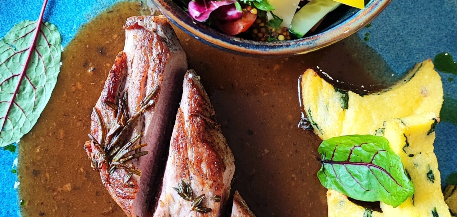 Stek podany z sosem, ziemniakami i świeżą sałatką z warzyw w ceramicznej misce