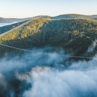 Widok na mglistą dolinę, otoczony gęstym lasem i pagórkami, idealny na przygodową wycieczkę.
