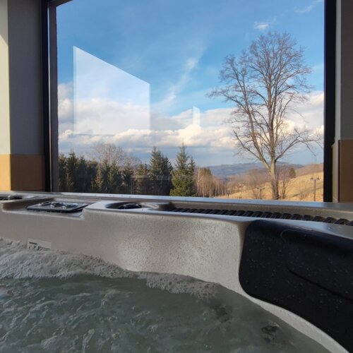 Hydromasaż w hotelowym jacuzzi z panoramicznym widokiem na drzewa i malownicze wzgórza w tle