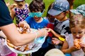Children outdoors in summer hats and sunglasses reach for powdered-sugar pastries from a tray during a casual snack.