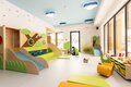 Bright hotel kids' playroom with indoor slides, ball pit, cloud lights, toys and a staff member playing with a child.
