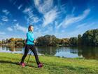 Gość uprawia nordic walking nad jeziorem, spokojna woda, jesienne drzewa i błękitne niebo - hotelowa trasa fitness