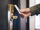 Ręka przykłada białą kartę do złotego elektronicznego zamka hotelowego z elegancką klamką, dostęp bez klucza