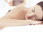 Woman resting face-down during a spa massage on white linens, relaxed atmosphere and soft natural light.