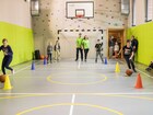 Indoor family sports hall with basketball hoop, climbing wall, padded green walls and supervised kids' dribbling drill.