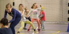 Dzieci przeciągają linę na krytej sali sportowej — radosna atrakcja klubu dla dzieci przy bramce
