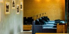 Przytulny salon hotelowy z niebieskimi sofami, czarnymi poduszkami, drewnianymi stopniami i dekoracyjnym drewnianym sufitem z ciepłym oświetleniem