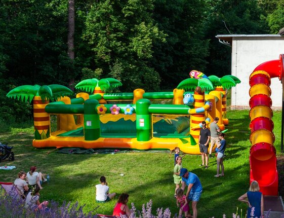 Colorful tropical inflatable play area with tube slide on the lawn, families and children enjoying a hotel outdoor zone