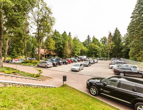 Hotel outdoor parking with many cars, paved entrance and tree-lined grounds offering a peaceful arrival.