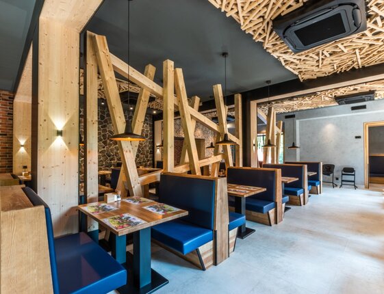 Contemporary hotel restaurant with wooden lattice ceiling, angled timber partitions, blue booths and warm pendant lighting.