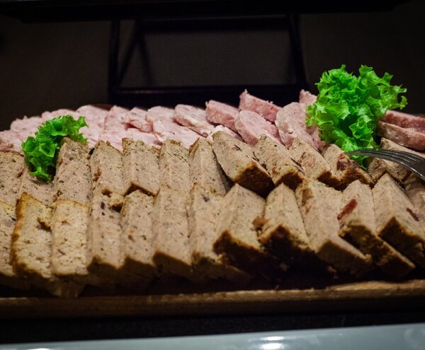 Platter of sliced pâté loaf and sliced cold meats arranged in rows, garnished with crisp lettuce for buffet service.