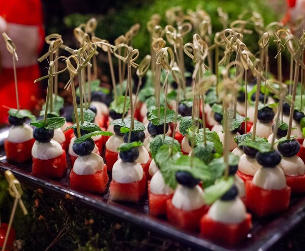 Mini szaszłyki z kostkami arbuza, kuleczkami mozzarelli, borówkami i miętą, podane jako przekąska koktajlowa