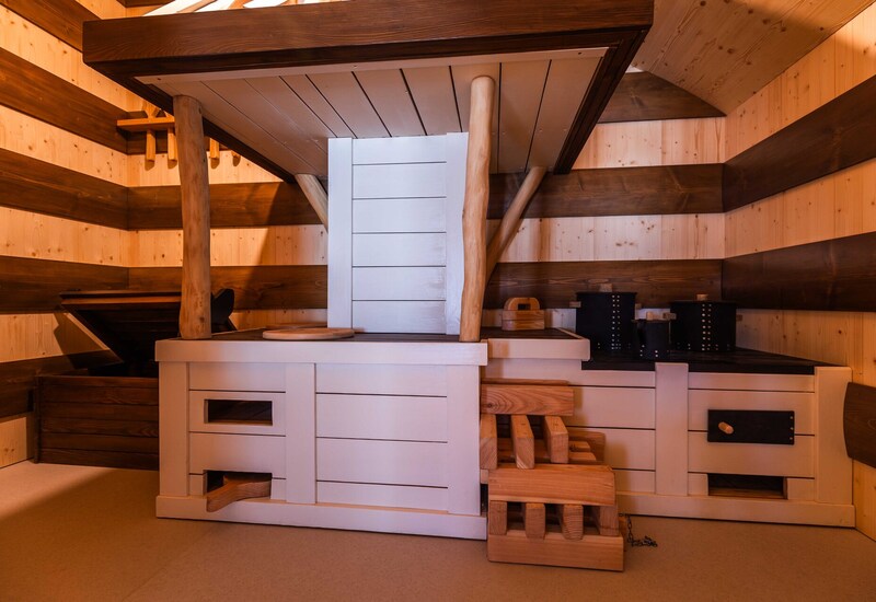 Sauna w drewnianym wnętrzu z piętrowymi ławkami, naturalnymi słupami i tradycyjnym piecem, ciepłe przytulne oświetlenie