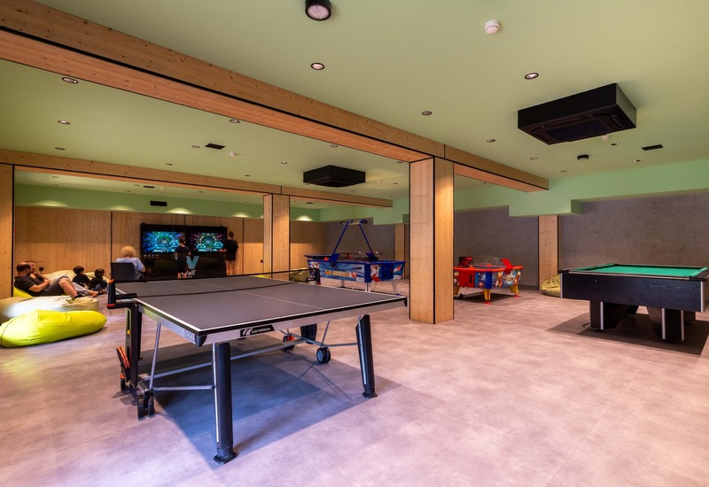 Sala gier hotelowa z ping-pongiem, bilardem, stołem air hockey, pufami i strefą gier przy telewizorze, drewniane belki