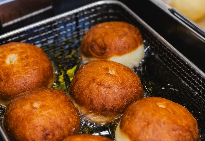 Złociste pączki smażone w profesjonalnej frytownicy, świeże wypieki na śniadanie lub do bufetu