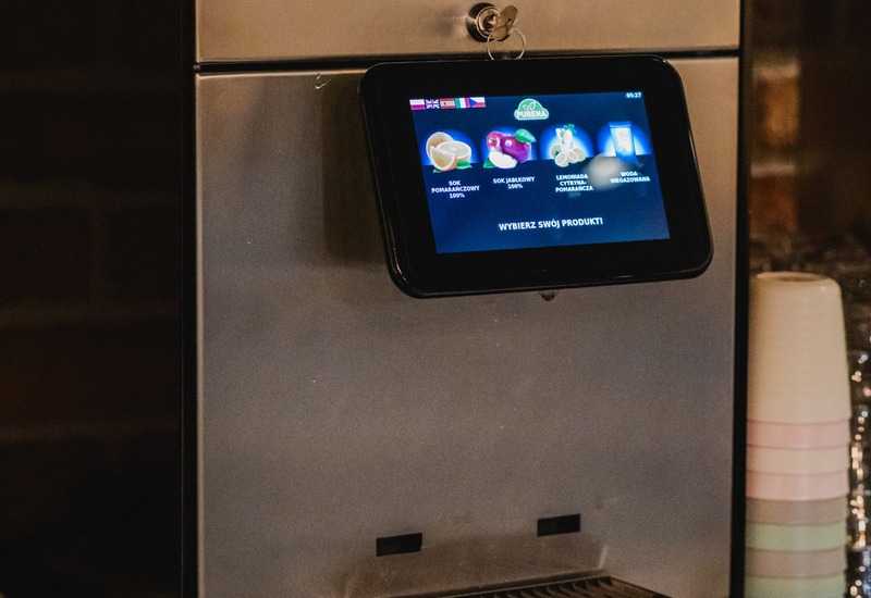 Automat do soków ze stali nierdzewnej z ekranem dotykowym i stoskiem jednorazowych kubków na bufecie śniadaniowym