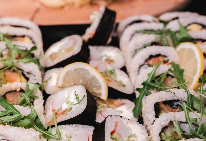 Świeże rolki sushi z plasterkami cytryny i rukolą na hotelowym bufecie