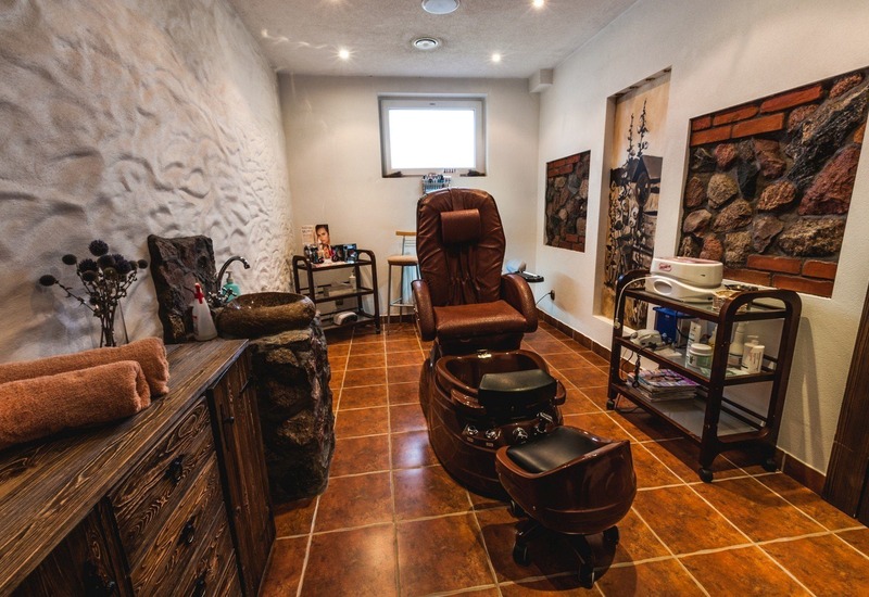 Przytulne spa z fotelem do pedicure w brązowej skórze, basenem do stóp, kamienną umywalką, drewnianymi szafkami i ręcznikami.