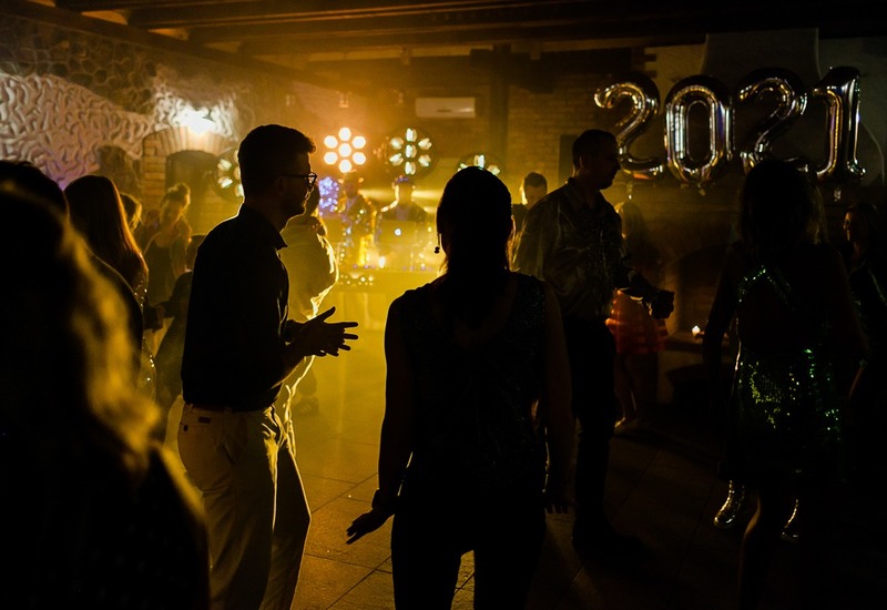 Sala bankietowa z parkietem, tańczący goście w półmroku przy stanowisku DJ, ciepłe światła i balony '2021'.