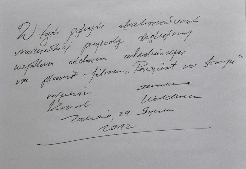Ręcznie pisana kursywą notatka w księdze gości na białym papierze, czarny atrament, podpis i data 2012, osobiste podziękowanie po polsku