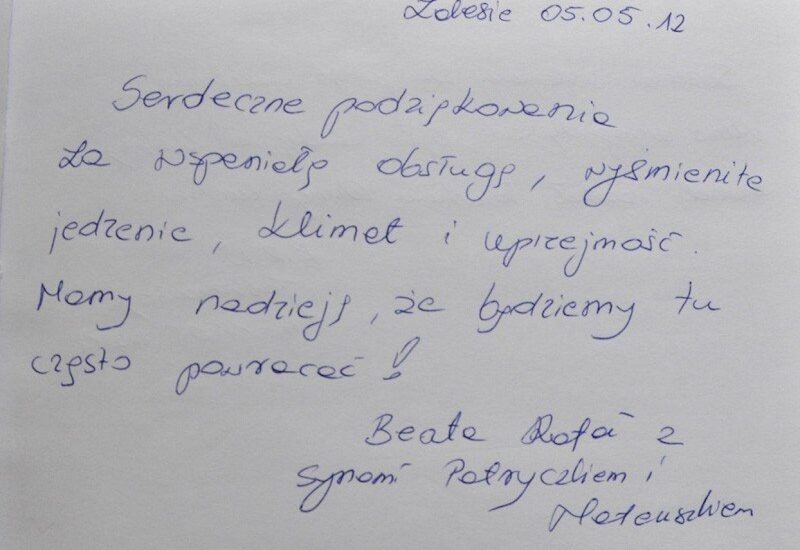 Ręczny wpis w księdze gości z datą, dziękujący za wspaniały pobyt, jedzenie i uprzejmość personelu, podpis gości.