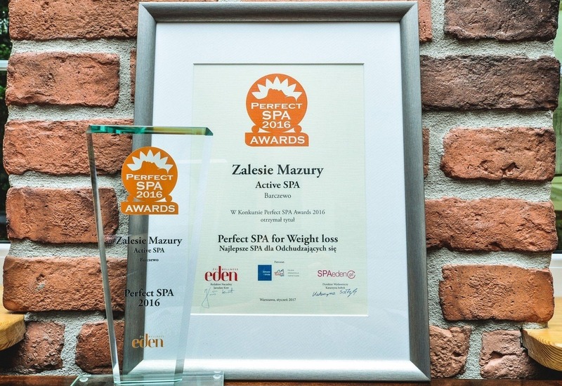 Oprawiony dyplom Perfect SPA 2016 i szklana statuetka na tle ceglanej ściany — Zalesie Mazury Active SPA nagrodzone za program odchudzający.