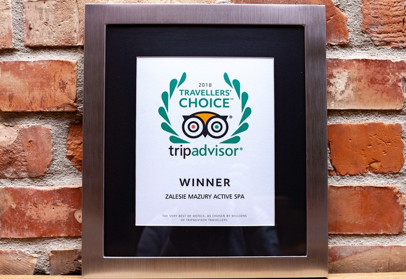 Oprawiony certyfikat Travellers' Choice 2018 TripAdvisor 'Winner' dla Zalesie Mazury Active Spa na ceglanej ścianie.