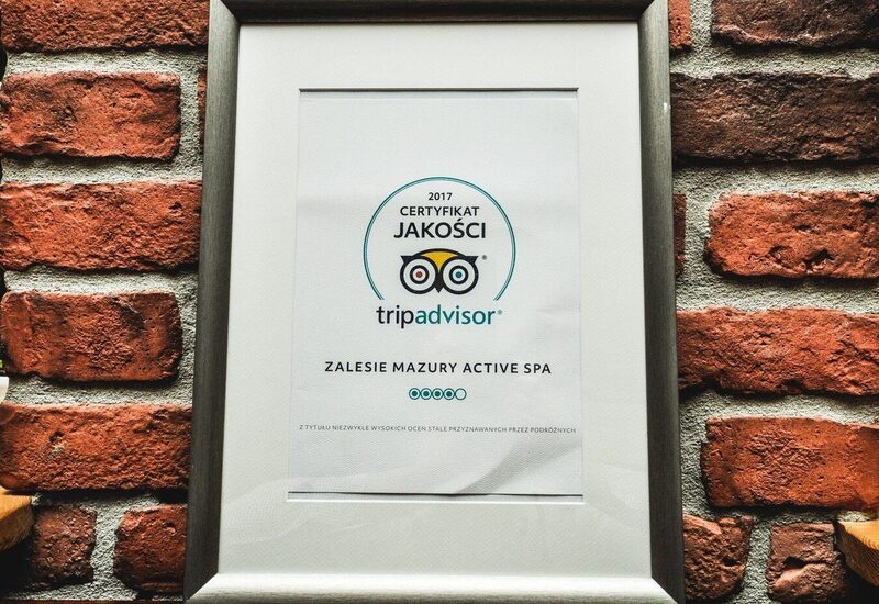 Certyfikat jakości TripAdvisor 2017 dla Zalesie Mazury Active Spa w srebrnej ramie na ciepłej ceglanej ścianie