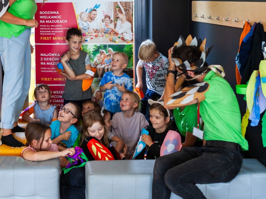 Klub dziecięcy: dzieci bawią się i robią prace plastyczne z animatorem w przebraniu w przyjaznej strefie zabaw hotelu.