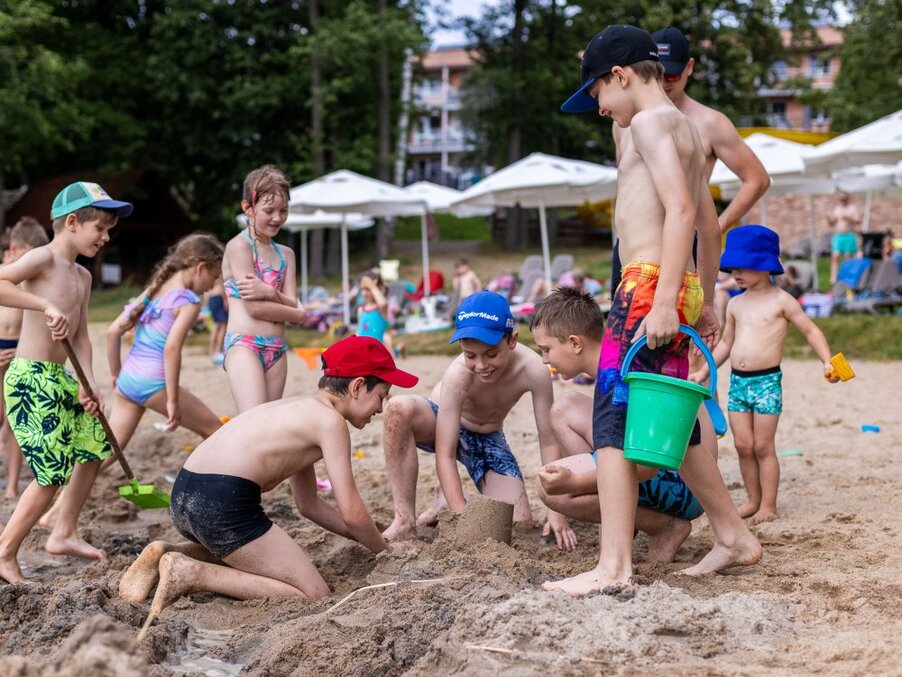 Kids building a sandcastle on a family-friendly hotel beach, colorful buckets, shovels and sun umbrellas.