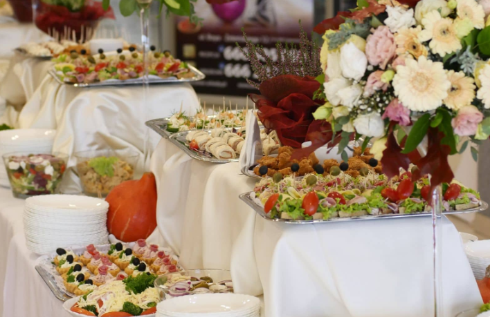 Bufet z różnorodnymi przekąskami i kanapkami na elegancko udekorowanym stole ze świeżymi kwiatami
