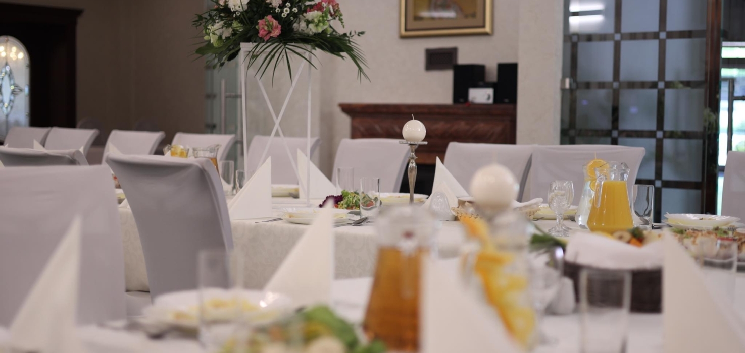 Elegancko nakryty stół z białymi obrusami i świeżymi kwiatami na bankiet w luksusowej sali restauracyjnej hotelu