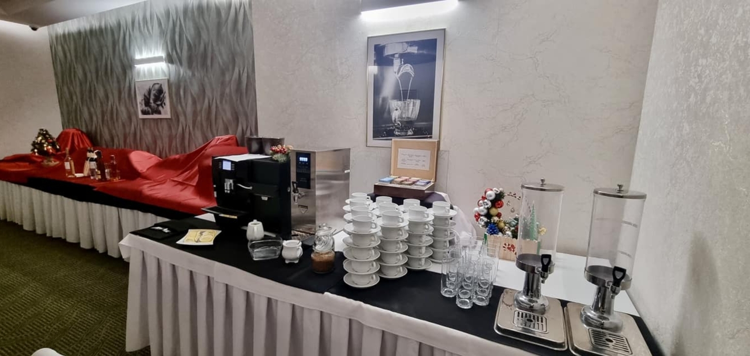Bufet kawowy w hotelu z ekspresami, filiżankami, dzbankami na napoje, dekoracjami świątecznymi i eleganckim wnętrzem