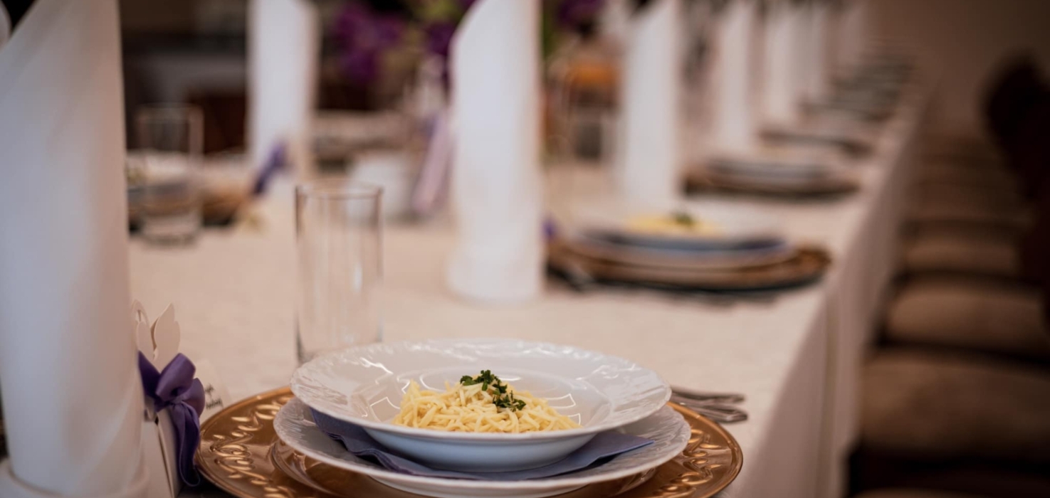 Elegancko zastawiony stół bankietowy z białymi serwetkami i talerzami z makaronem, w przytulnej sali bankietowej